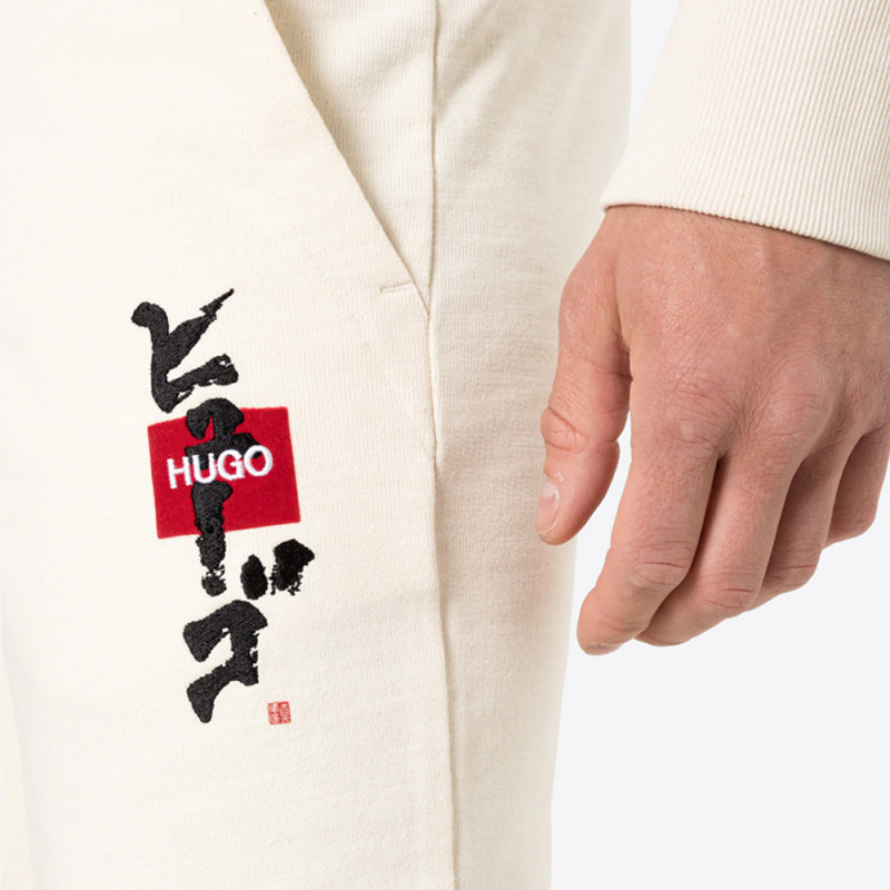 Pantalon de survêtement Dohagi beige en molleton avec logo et motif calligraphique artistique