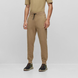 BAS DE SURVÊTEMENT RESSERRÉ AU BAS DES JAMBES EN MOLLETON ORNÉ D’UN BADGE LOGO